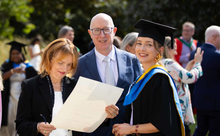 A UCD alumna celebrating her graduation with her parents.